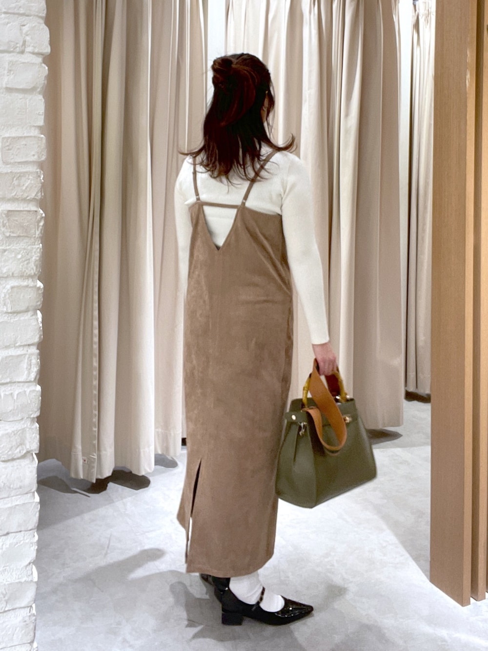 ホワイト系のニット/セーター、ブラウン系のワンピース、グリーン系のショルダーバッグを着用したレディースの冬コーディネートの4枚目の写真