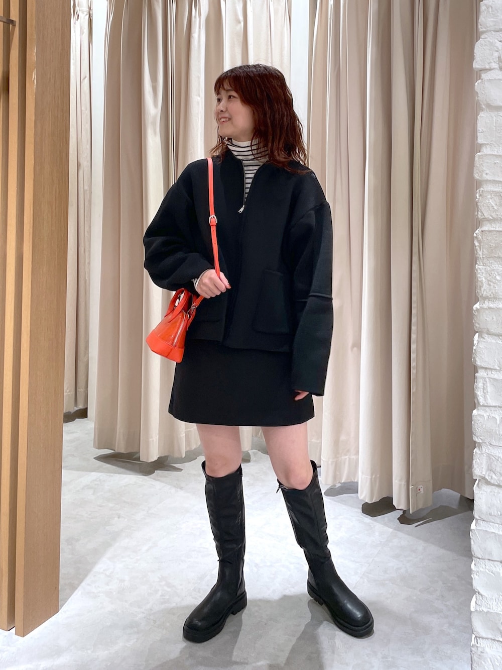 ホワイト系のニット/セーター、ブラック系のカーディガン/ボレロ、ブラック系のブーツを着用したレディースの秋コーディネートの4枚目の写真