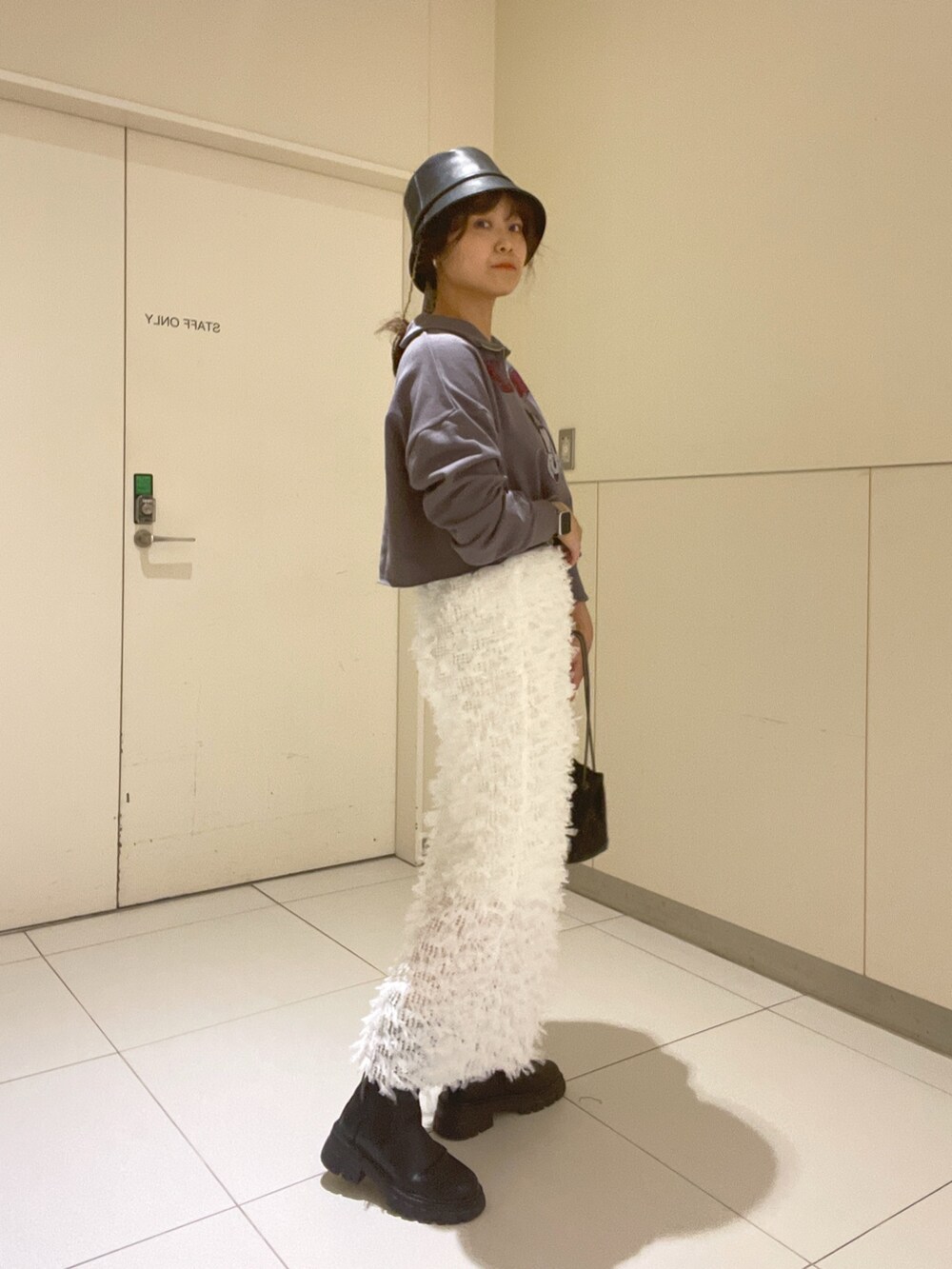 ブラック系のスウェット、ブラック系のショルダーバッグ、ホワイト系のスカートを着用したレディースの秋コーディネートの2枚目の写真