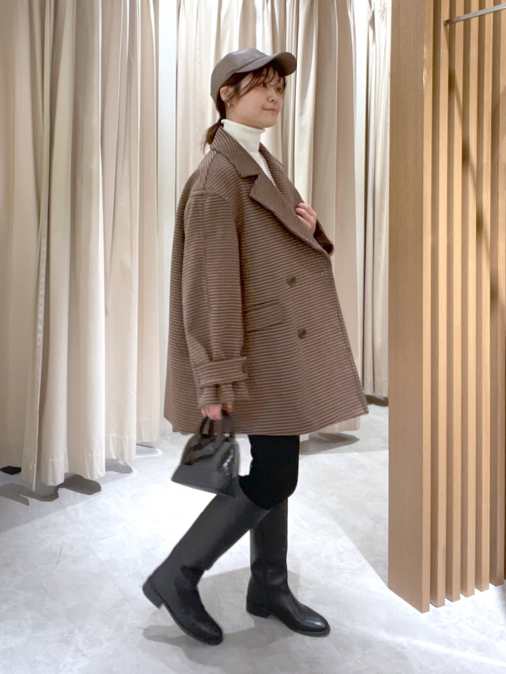 ベージュ系のピーコート、ホワイト系のニット/セーター、ブラック系のショルダーバッグを着用したレディースの冬コーディネートの3枚目の写真