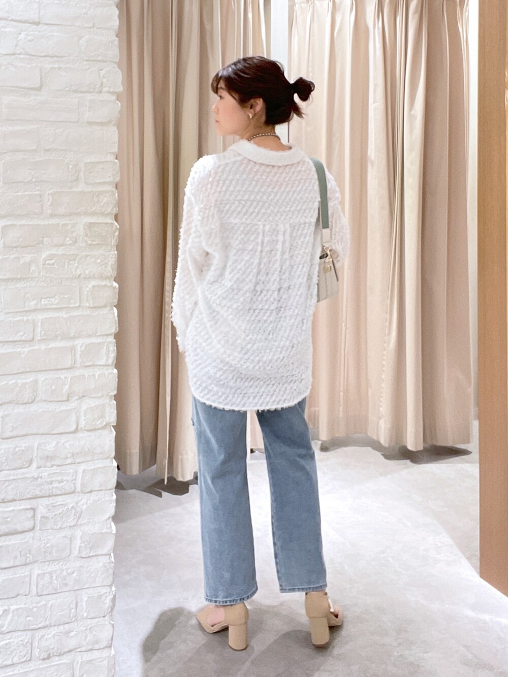 ホワイト系のシャツ/ブラウス、ブルー系のデニムパンツ、ホワイト系のショルダーバッグを着用したレディースの春コーディネートの4枚目の写真