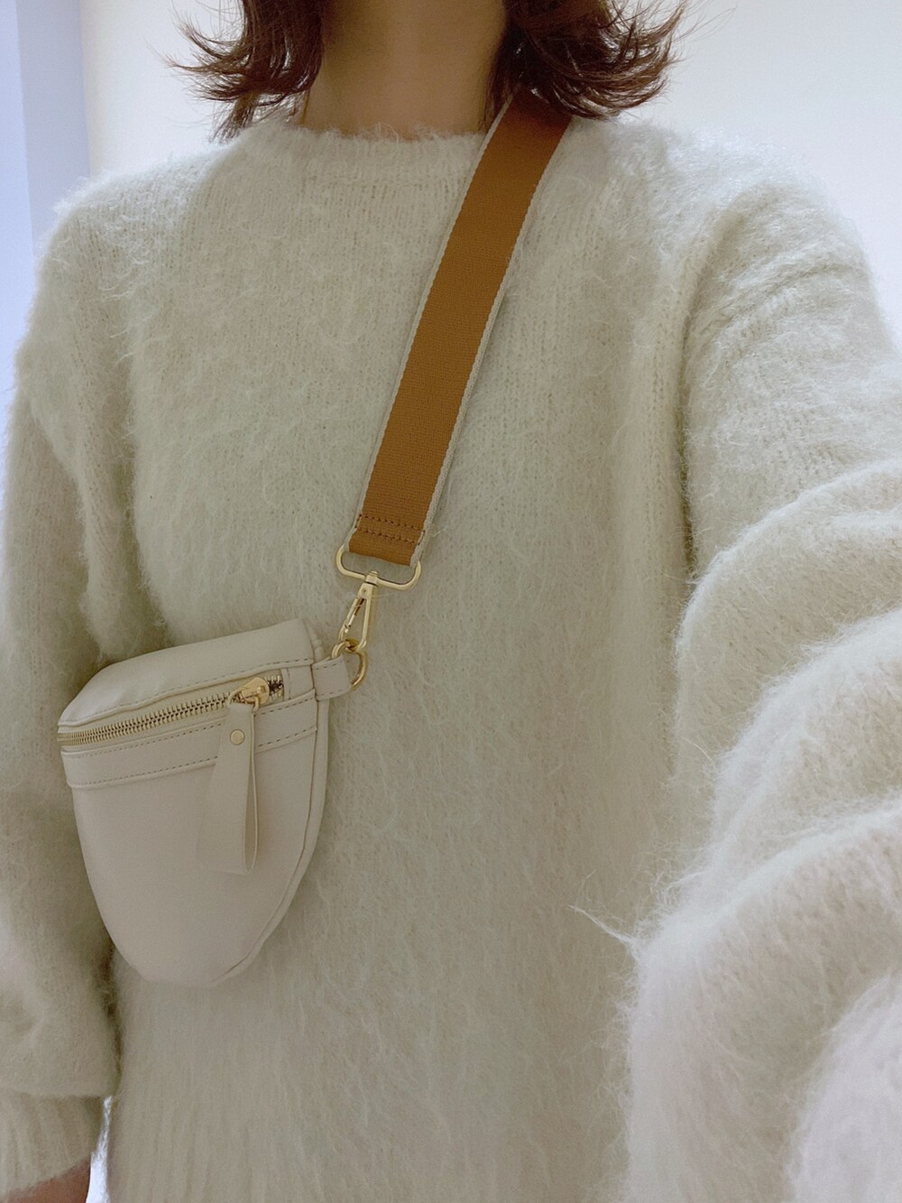 ホワイト系のニット/セーター、シルバー系のスカート、ホワイト系のブーツを着用したレディースの冬コーディネートの4枚目の写真