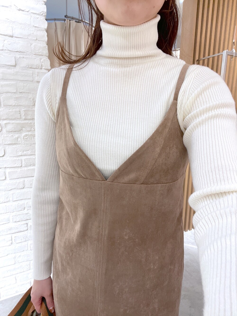 ホワイト系のニット/セーター、ブラウン系のワンピース、グリーン系のショルダーバッグを着用したレディースの冬コーディネートの5枚目の写真