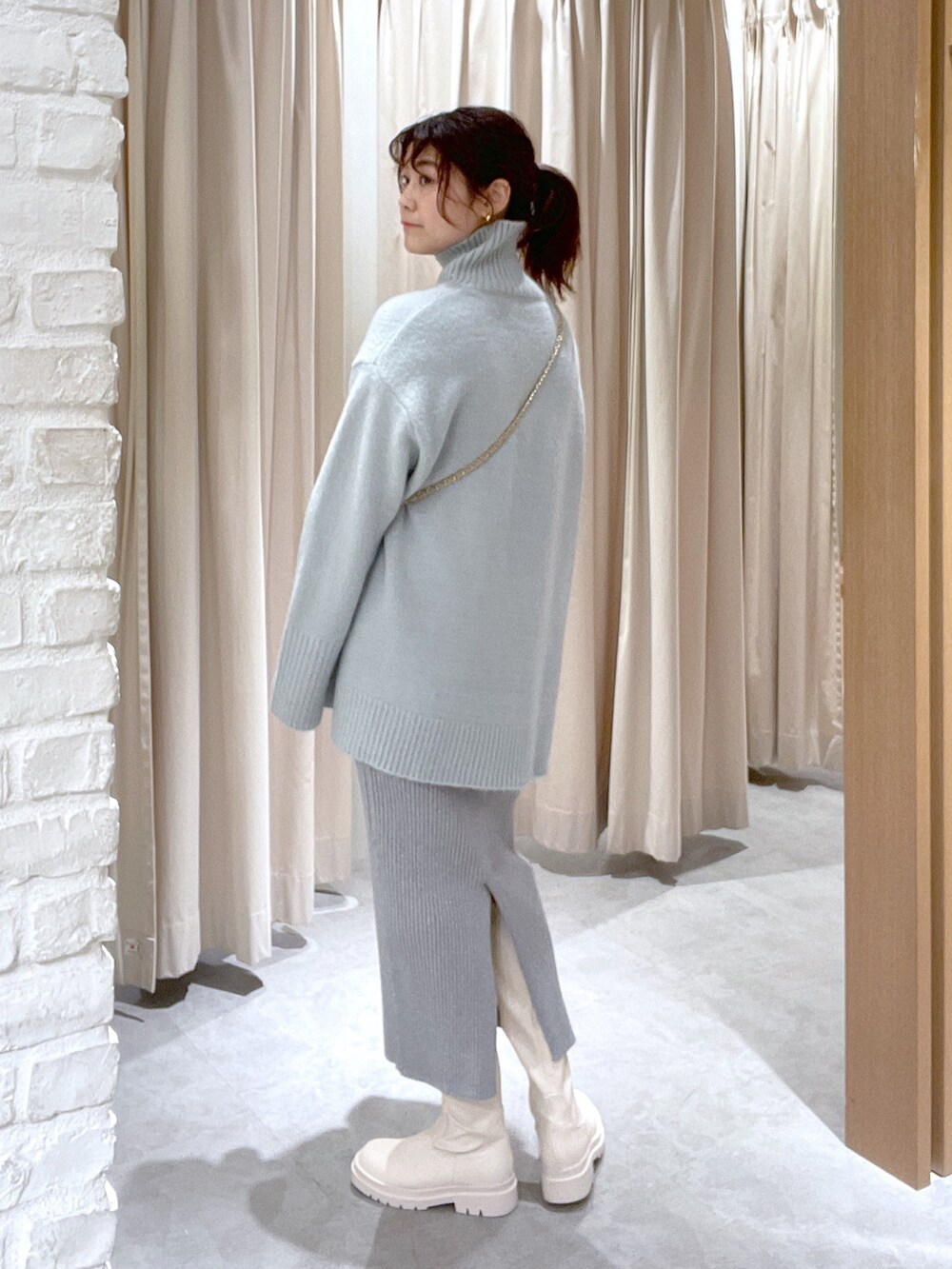 グリーン系のニット/セーター、シルバー系のスカート、ホワイト系のブーツを着用したレディースの冬コーディネートの4枚目の写真