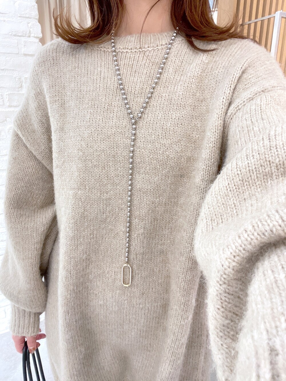 ベージュ系のワンピース、ブラック系のハンドバッグを着用したレディースの冬コーディネートの6枚目の写真