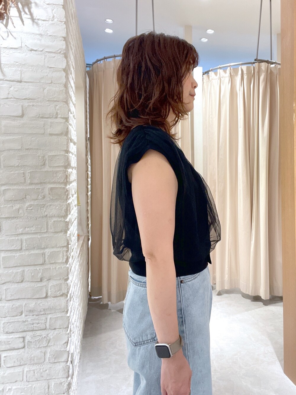 ブラック系のベスト、ブルー系のデニムパンツ、ブラック系のサンダルを着用したレディースの夏コーディネートの4枚目の写真