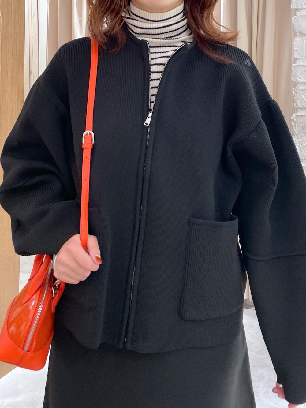 ホワイト系のニット/セーター、ブラック系のカーディガン/ボレロ、ブラック系のブーツを着用したレディースの秋コーディネートの5枚目の写真