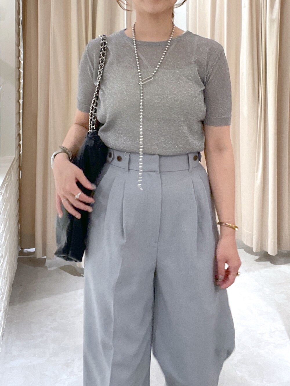 シルバー系のニット/セーター、グレー系のスラックス、ブラック系のサンダルを着用したレディースの夏コーディネートの5枚目の写真