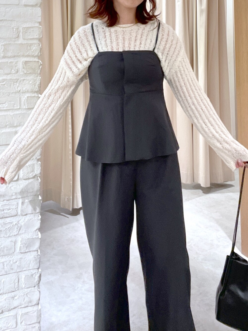 ホワイト系のニット/セーター、ブラック系のシャツ/ブラウス、ブラック系のスラックスを着用したレディースの春コーディネートの4枚目の写真