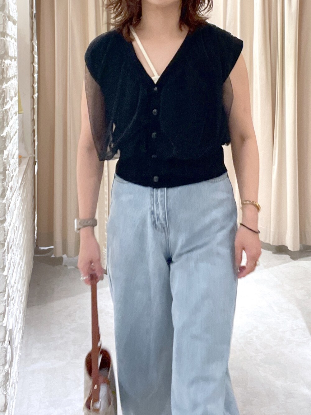 ブラック系のベスト、ブルー系のデニムパンツ、ブラック系のサンダルを着用したレディースの夏コーディネートの5枚目の写真