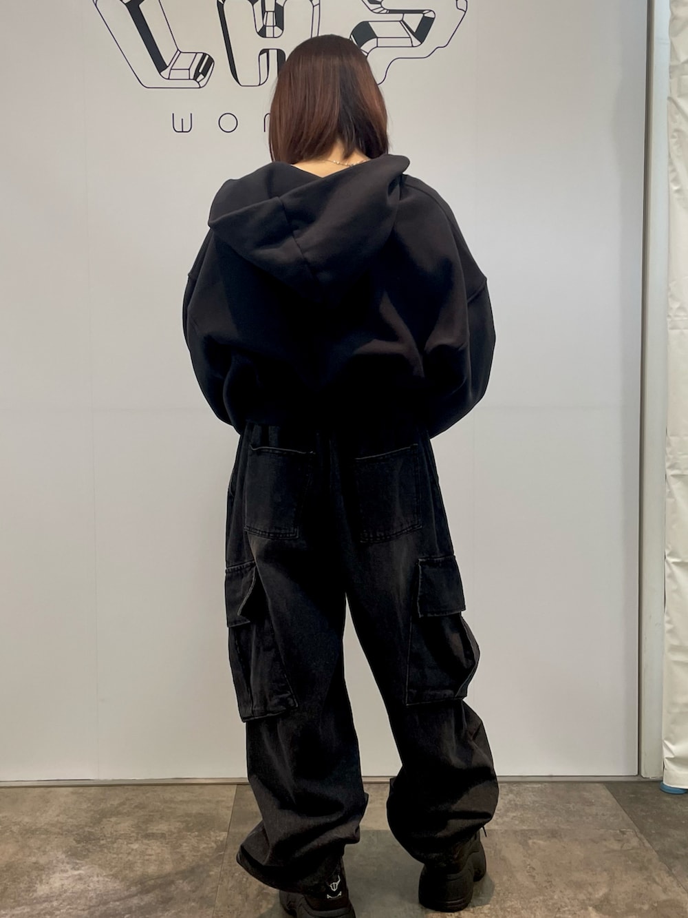 ブラック系のパーカー、ブラック系のブーツ、ブラック系のデニムパンツを着用したレディースの春コーディネートの2枚目の写真