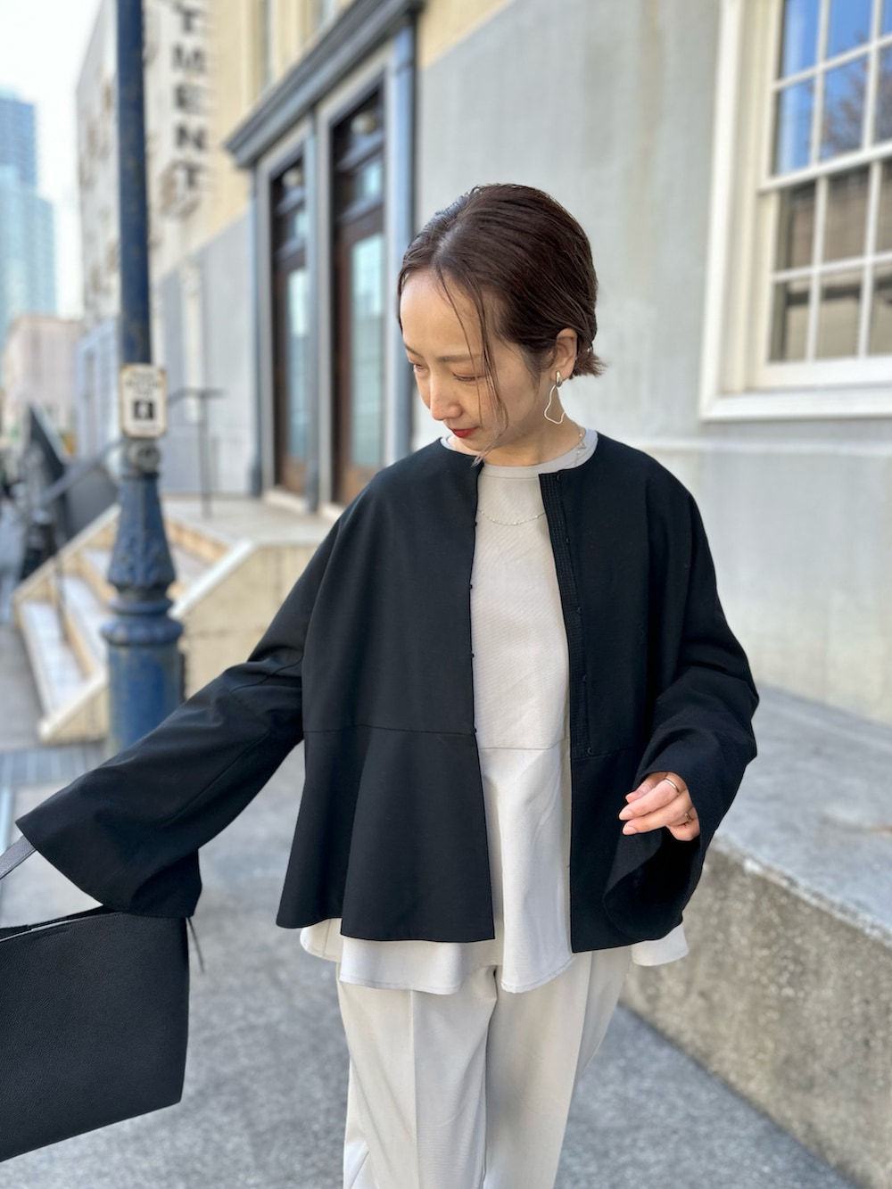 ブラック系のノーカラージャケット、ベージュ系のスーツセット、ベージュ系のショルダーバッグを着用したレディースの冬コーディネートの2枚目の写真