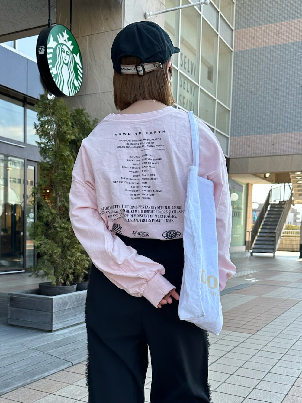 ピンク系のTシャツ/カットソー、ブラック系のスラックス、ブラック系のキャップを着用したレディースの春コーディネートの2枚目の写真
