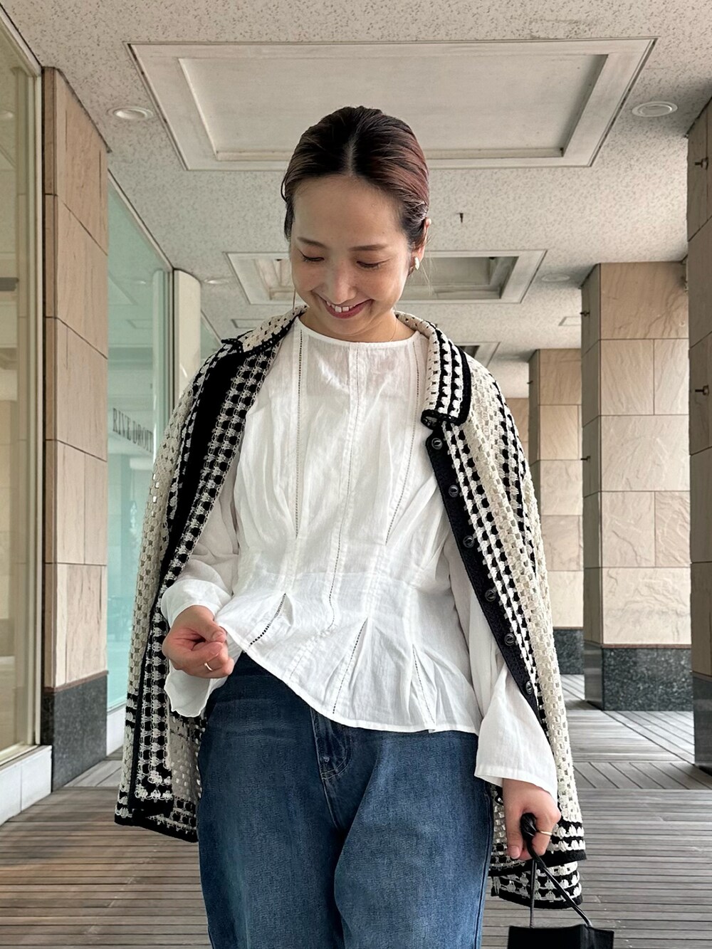 ホワイト系のシャツ/ブラウス、ホワイト系のカーディガン/ボレロ、ブルー系のデニムパンツを着用したレディースの秋コーディネートの2枚目の写真