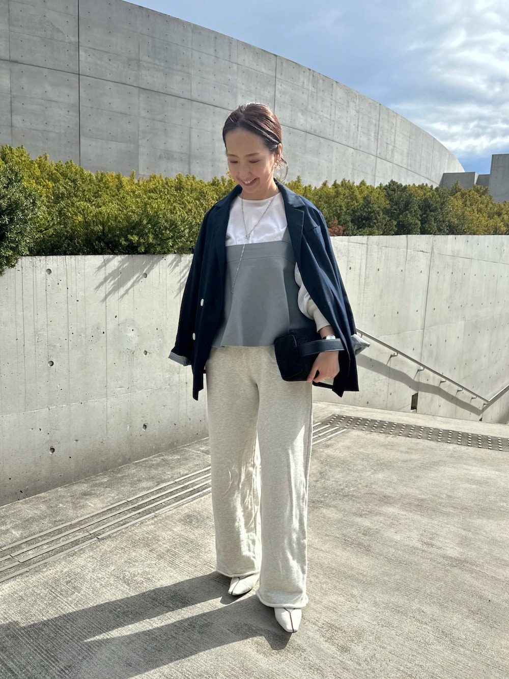 グレー系のニット/セーター、ベージュ系のスウェットパンツ、ホワイト系のシャツ/ブラウスを着用したレディースの春コーディネートの2枚目の写真