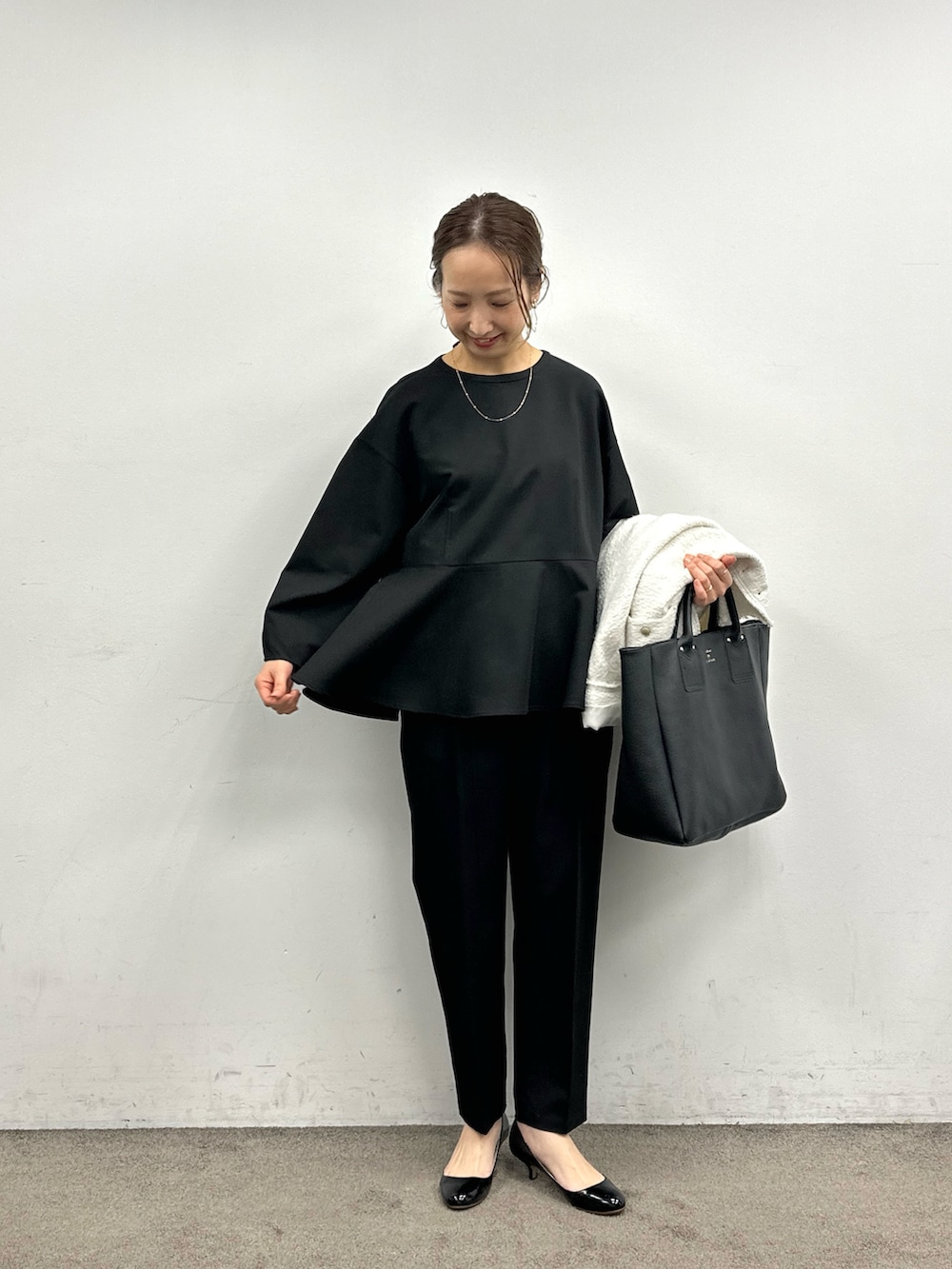 ブラック系のスーツセット、ホワイト系のノーカラージャケット、ブラック系のトートバッグを着用したレディースの冬コーディネートの2枚目の写真