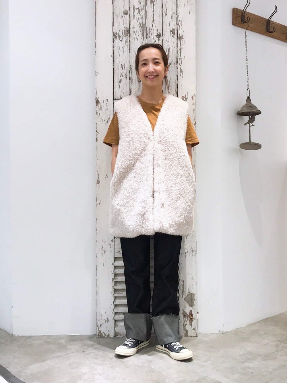 ホワイト系のベスト、ブラック系のデニムパンツ、ブラック系のスニーカーを着用したレディースの夏コーディネートの3枚目の写真