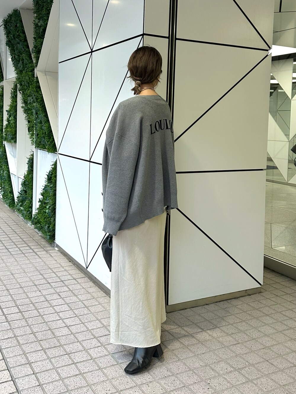 ホワイト系のTシャツ/カットソー、グレー系のニット/セーター、ベージュ系のスカートを着用したレディースの秋コーディネートの2枚目の写真