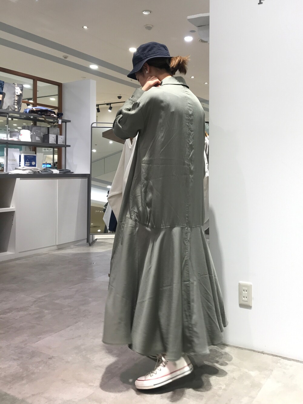 グリーン系のワンピース、ホワイト系のスニーカー、ホワイト系のハットを着用したレディースの春コーディネートの2枚目の写真