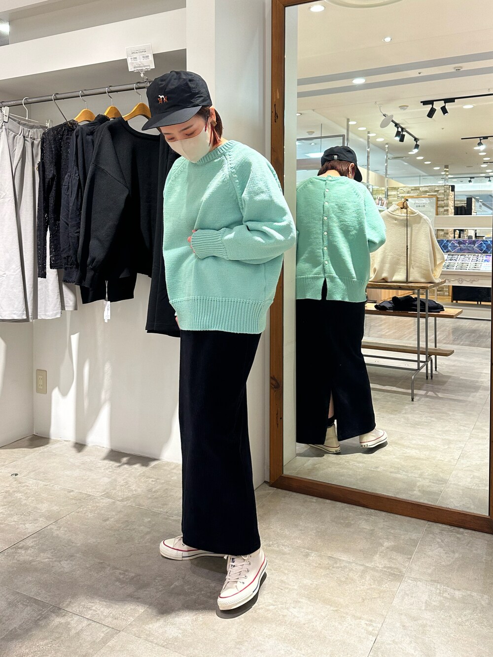 グリーン系のニット/セーター、ブラック系のスカート、ブラック系のキャップを着用したレディースの冬コーディネートの2枚目の写真