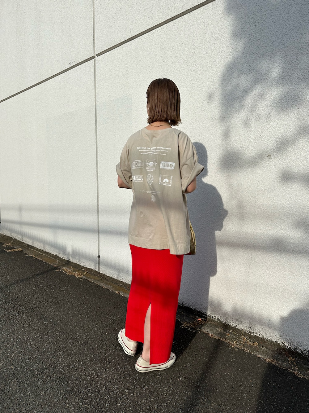 ベージュ系のTシャツ/カットソー、レッド系のスカート、ゴールド系のバッグを着用したレディースの春コーディネートの2枚目の写真