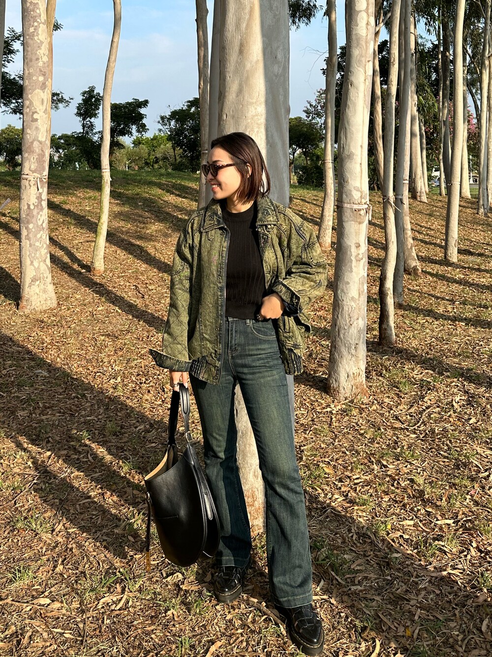 ブラック系のショルダーバッグ、ブラック系のサンダル、ブルー系のデニムパンツを着用したレディースの冬コーディネートの2枚目の写真