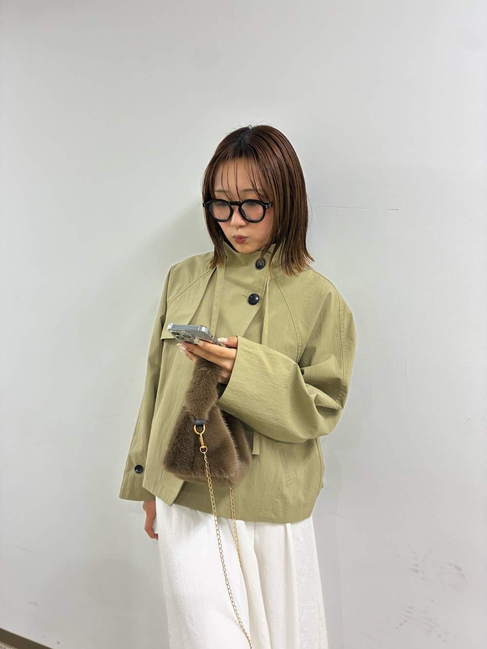 ベージュ系のトレンチコート、ホワイト系のスカートを着用したレディースの冬コーディネートの3枚目の写真