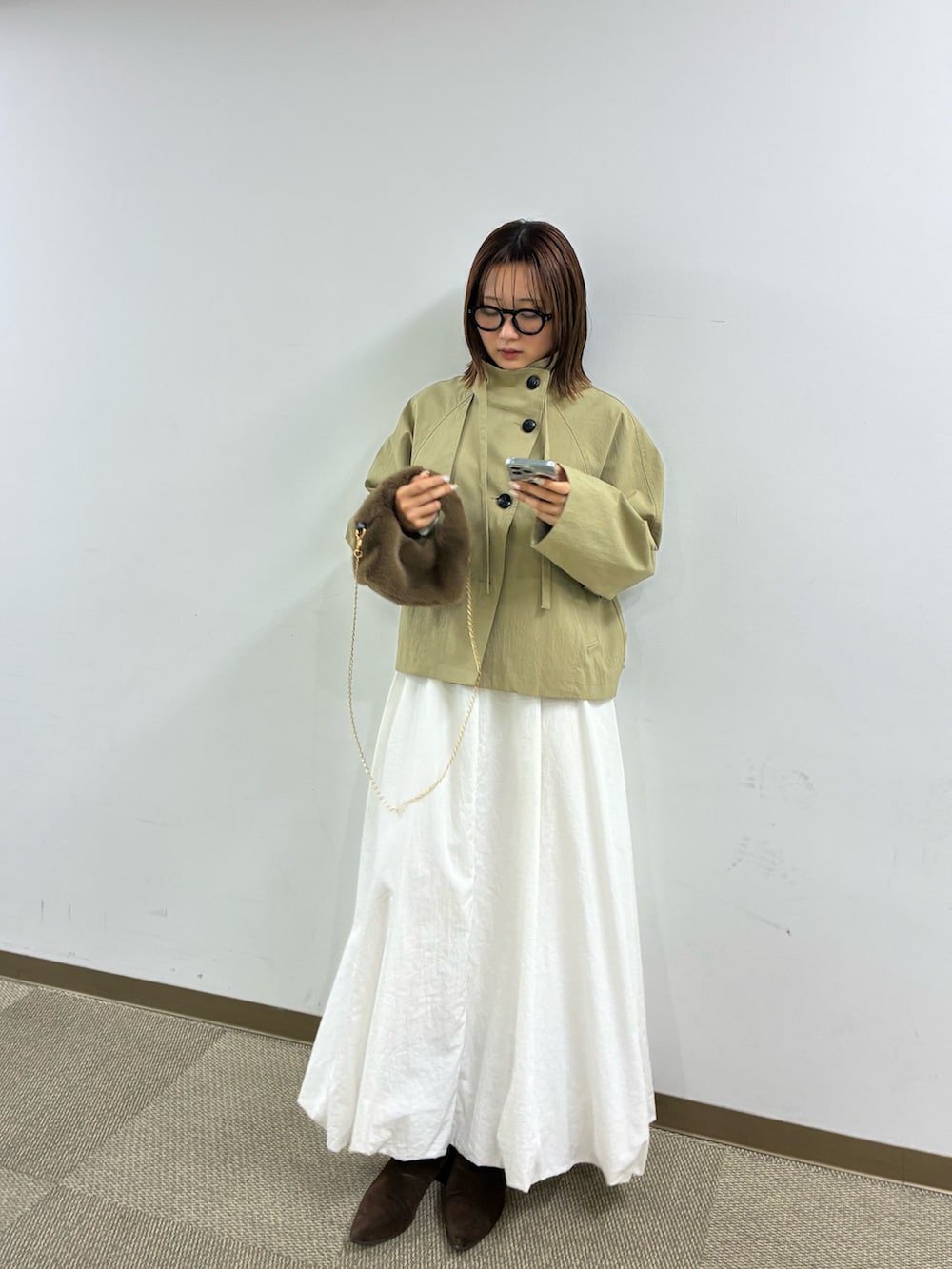 ベージュ系のトレンチコート、ホワイト系のスカートを着用したレディースの冬コーディネートの2枚目の写真