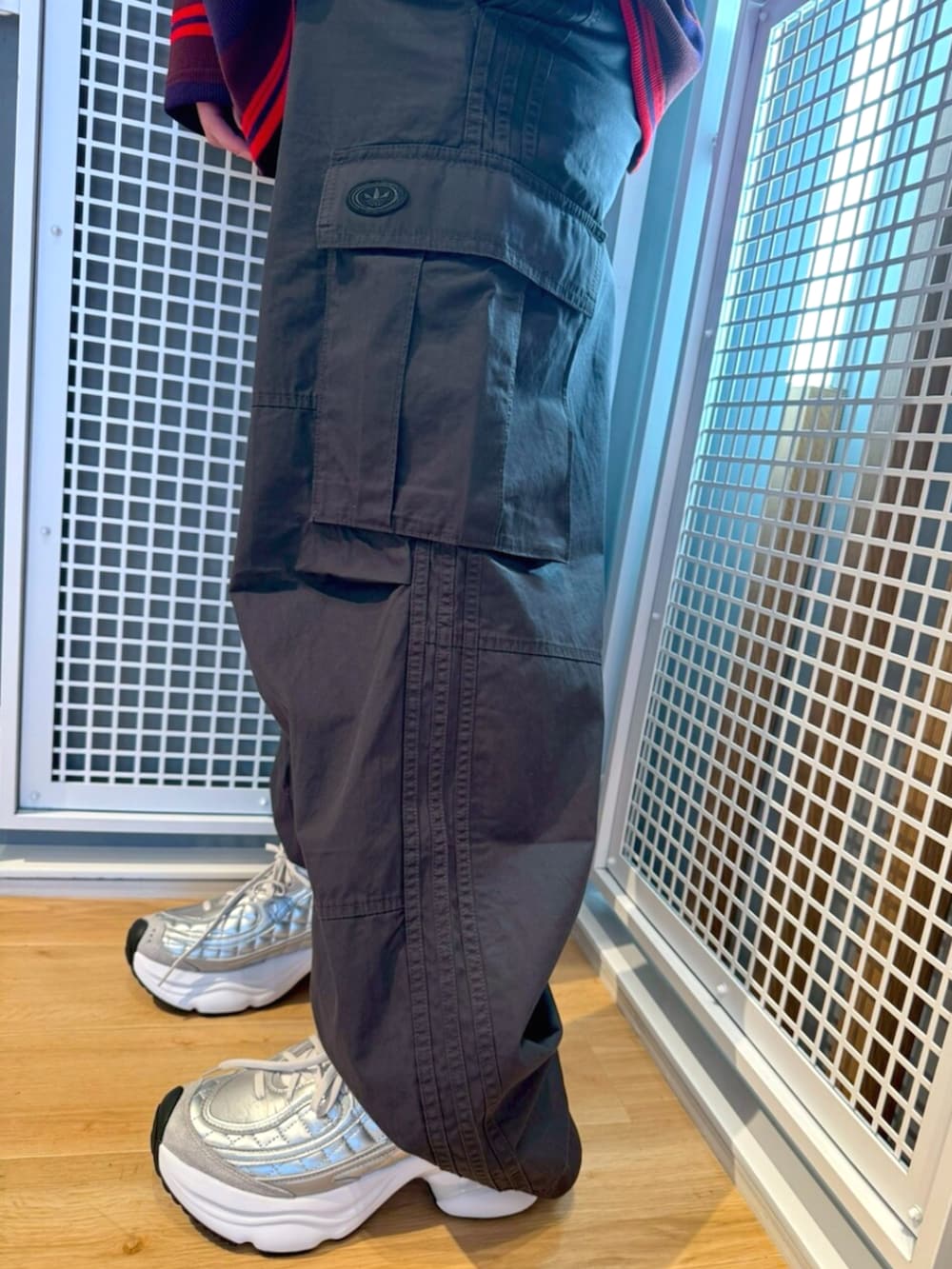 グレー系のその他パンツ、レッド系のTシャツ/カットソー、ホワイト系のスニーカーを着用したメンズの冬コーディネートの3枚目の写真