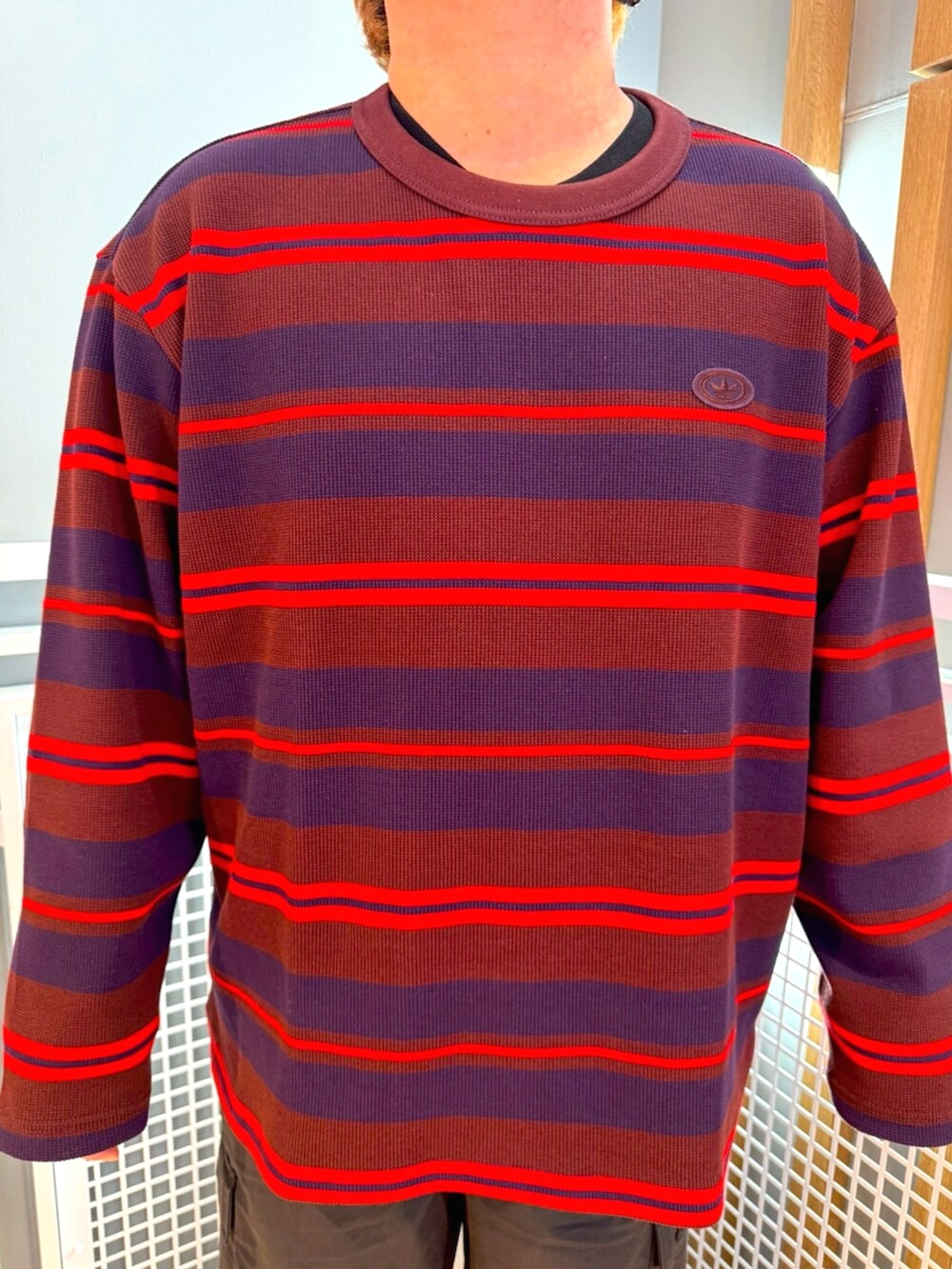 グレー系のその他パンツ、レッド系のTシャツ/カットソー、ホワイト系のスニーカーを着用したメンズの冬コーディネートの2枚目の写真