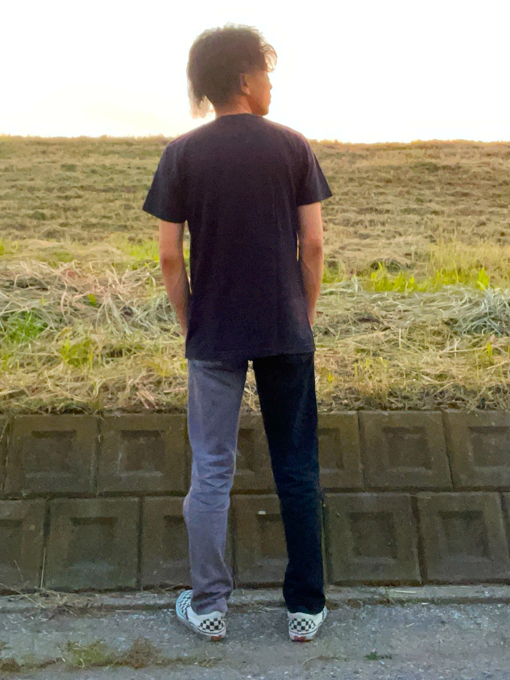 ブラック系のTシャツ/カットソー、ブラック系のデニムパンツ、ホワイト系のスニーカーを着用したメンズの秋コーディネートの3枚目の写真