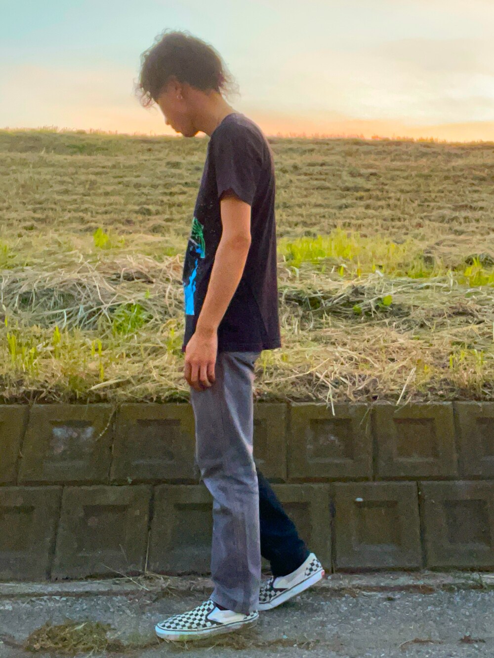 ブラック系のTシャツ/カットソー、ブラック系のデニムパンツ、ホワイト系のスニーカーを着用したメンズの秋コーディネートの2枚目の写真