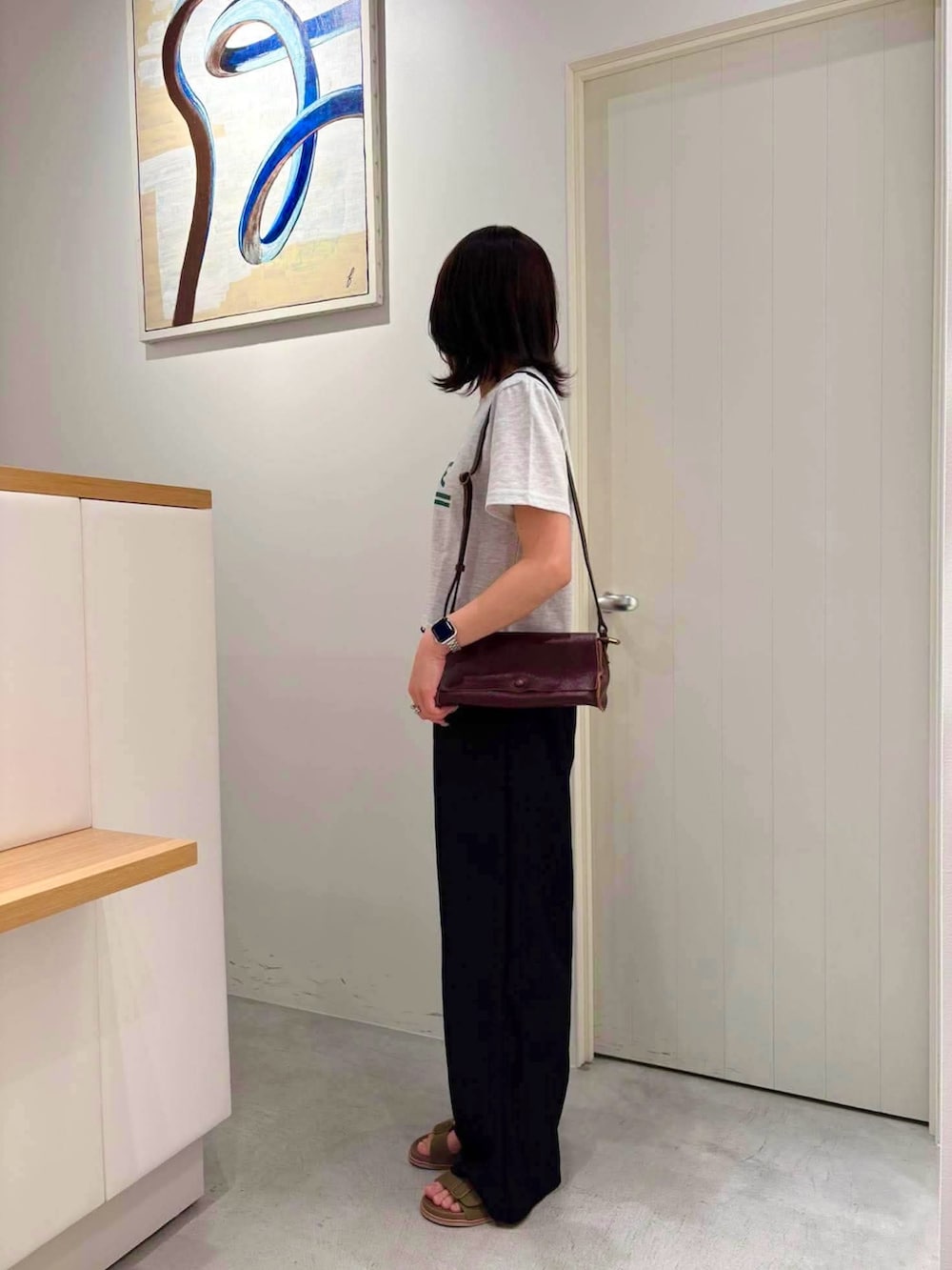 グレー系のTシャツ/カットソー、ブラウン系のショルダーバッグ、グリーン系のサンダルを着用したレディースの夏コーディネートの2枚目の写真