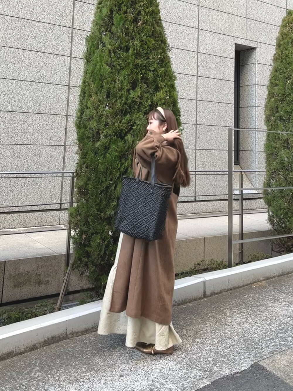 ブラック系のバッグ、ベージュ系のワンピース、ゴールド系のパンプスを着用したレディースの冬コーディネートの2枚目の写真