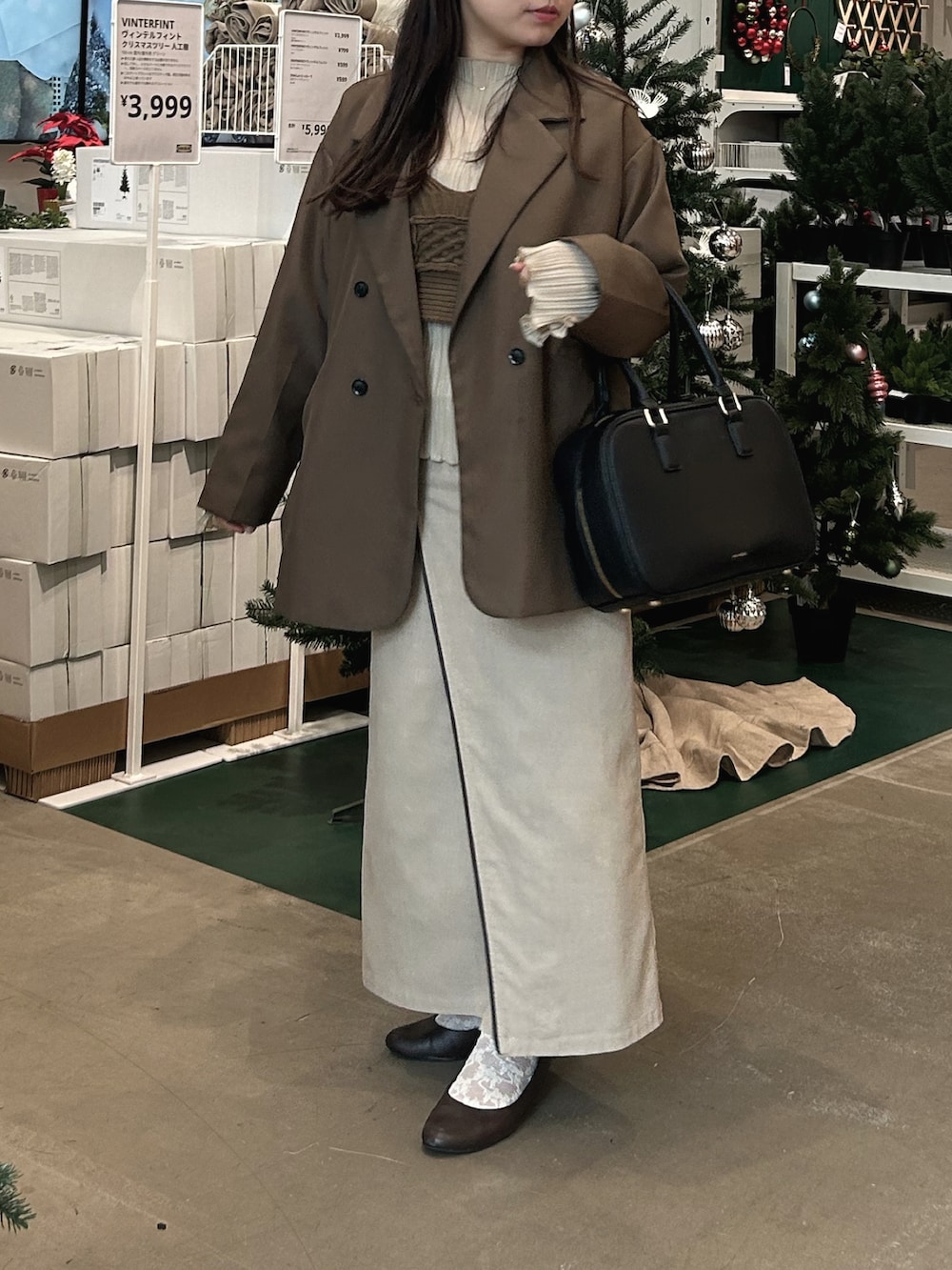 ブラウン系のテーラードジャケット、ブラック系のボストンバッグ、ベージュ系のスカートを着用したレディースの冬コーディネートの2枚目の写真