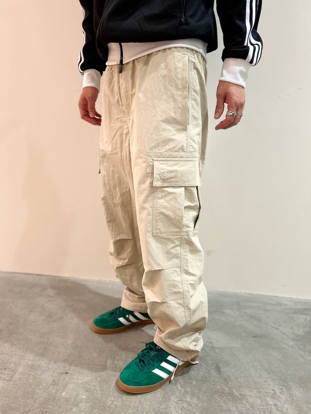 ベージュ系のカーゴパンツ、ブラック系のジャージ、グリーン系のスニーカーを着用したメンズの夏コーディネートの3枚目の写真