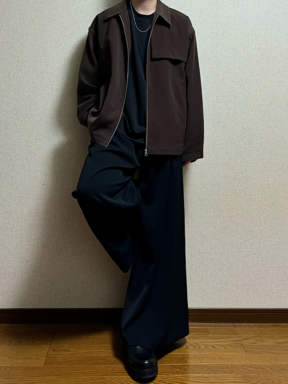 ブラウン系のブルゾン、ブラック系のTシャツ/カットソー、ブラック系のスラックスを着用したメンズの春コーディネートの2枚目の写真