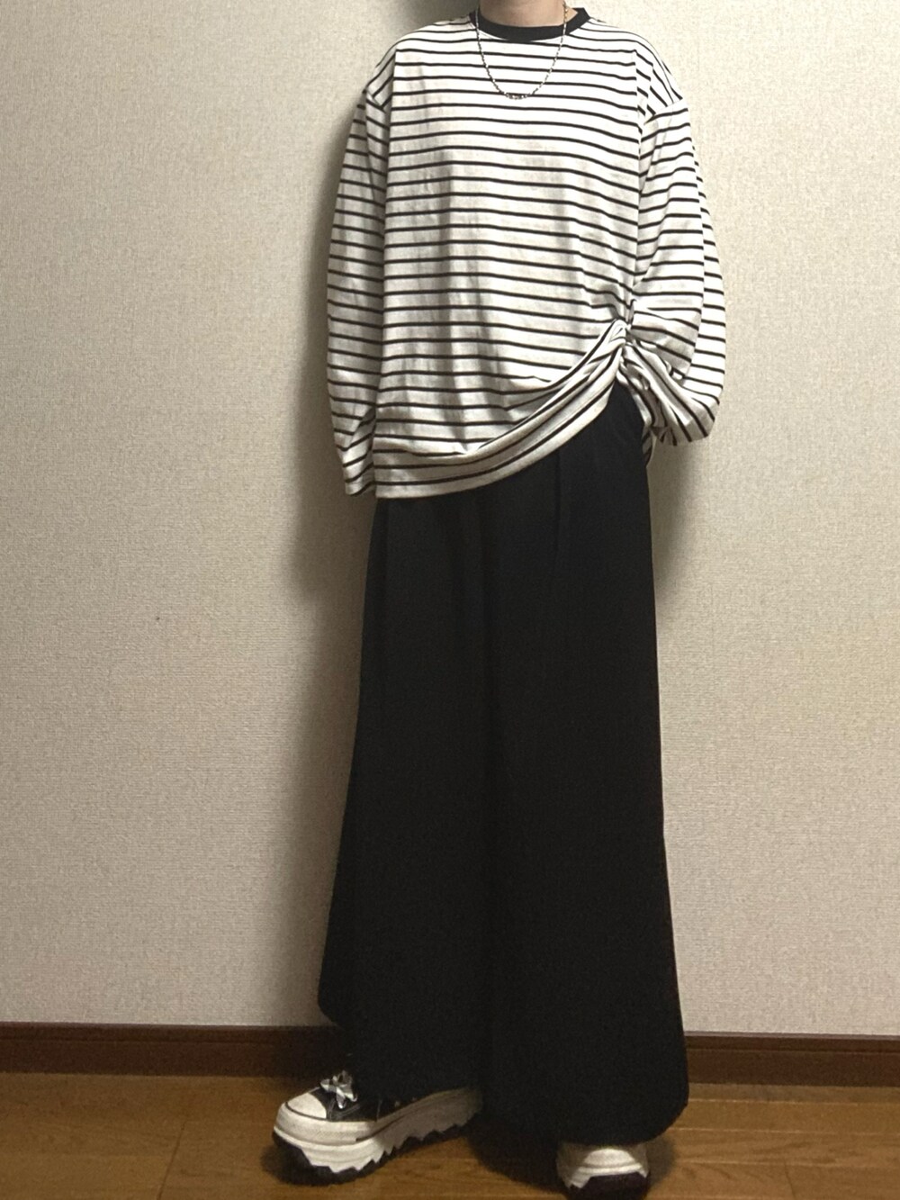 ブラック系のスニーカー、ブラック系のスラックス、ホワイト系のTシャツ/カットソーを着用したメンズの冬コーディネートの2枚目の写真