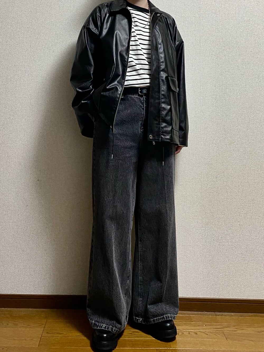 ブラック系のデニムパンツ、ブラック系のドレスシューズ、ブラック系のブルゾンを着用したメンズの春コーディネートの3枚目の写真