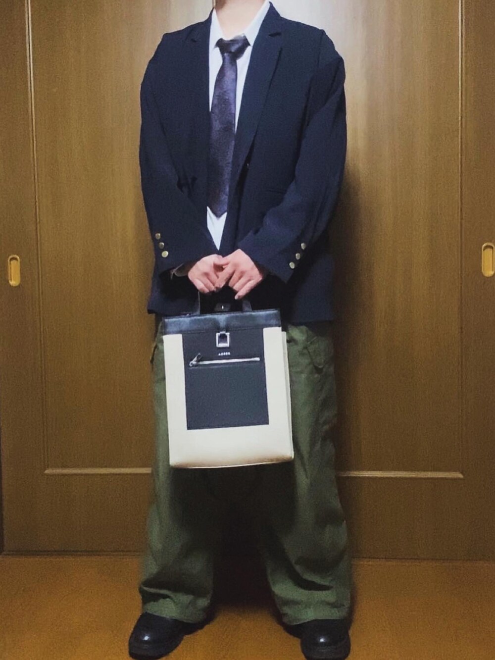 ベージュ系のトートバッグ、ブルー系のテーラードジャケット、ブルー系のネクタイを着用したメンズの冬コーディネートの2枚目の写真