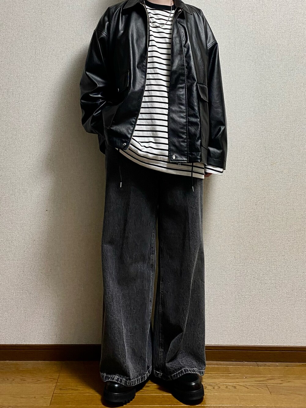 ブラック系のデニムパンツ、ブラック系のドレスシューズ、ブラック系のブルゾンを着用したメンズの春コーディネートの2枚目の写真