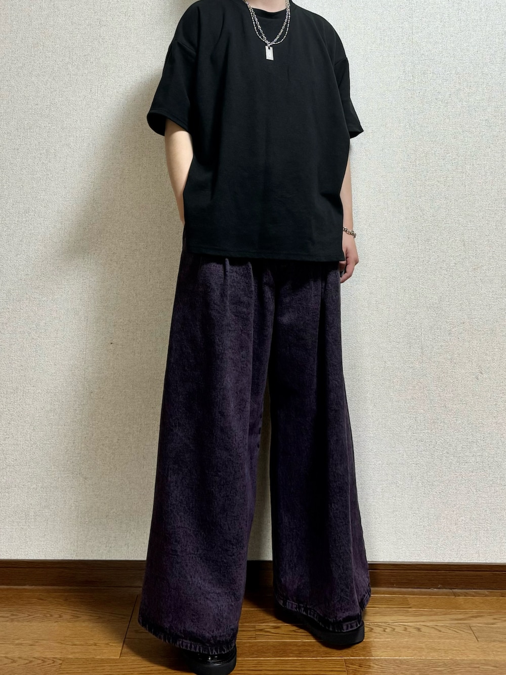 パープル系のデニムパンツ、ブラック系のTシャツ/カットソー、ブラック系のサンダルを着用したメンズの春コーディネートの2枚目の写真