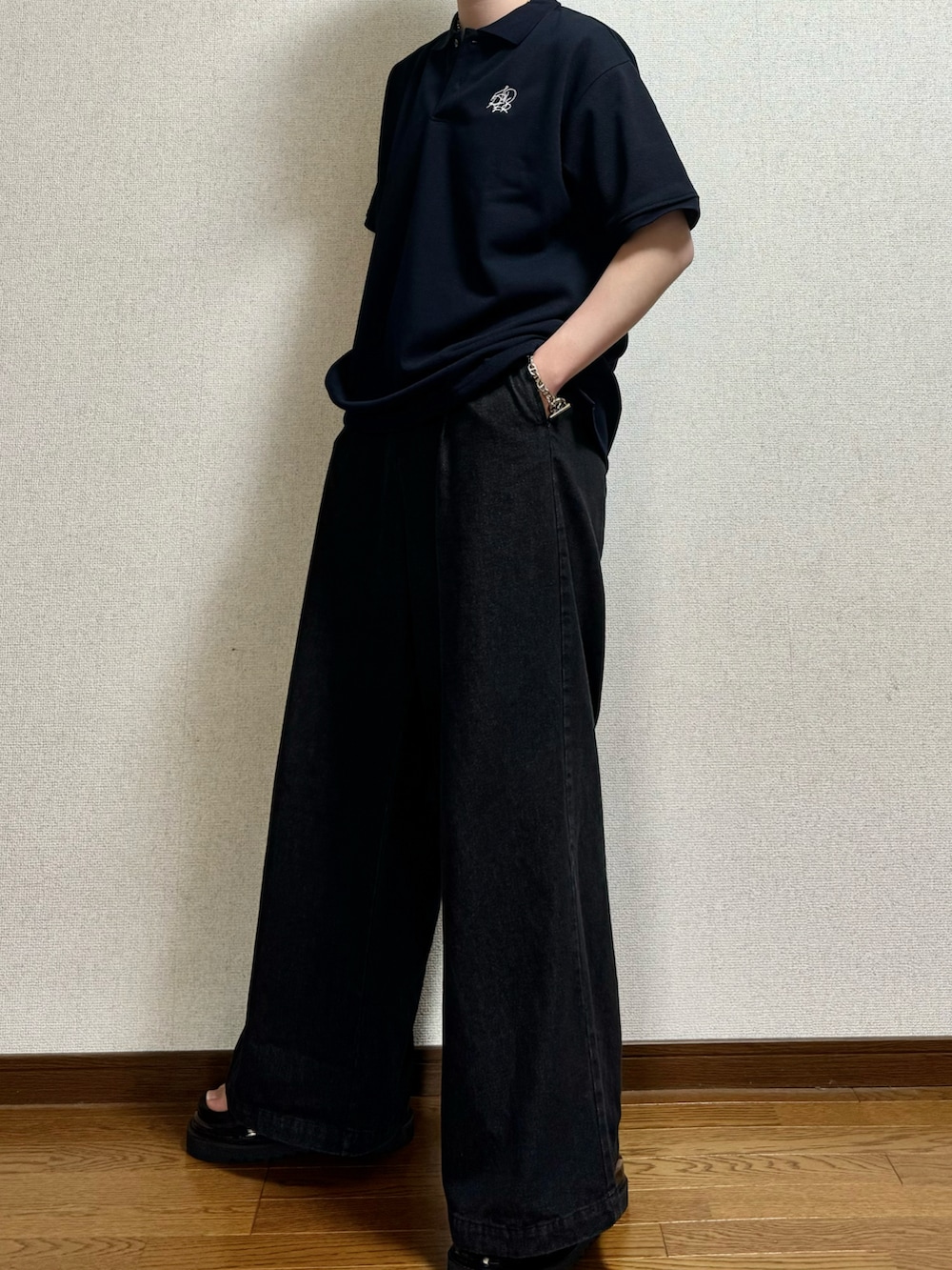 ブルー系のポロシャツ、ブラック系のデニムパンツ、ブラック系のサンダルを着用したメンズの春コーディネートの2枚目の写真