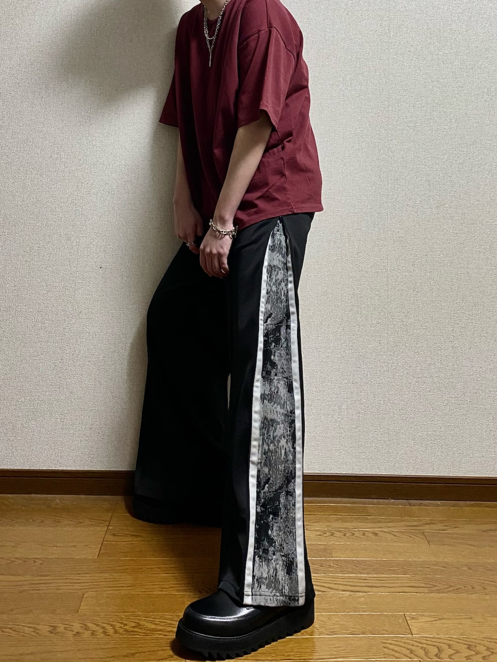 ブラック系のその他パンツ、ブラック系のドレスシューズ、レッド系のTシャツ/カットソーを着用したメンズの春コーディネートの4枚目の写真