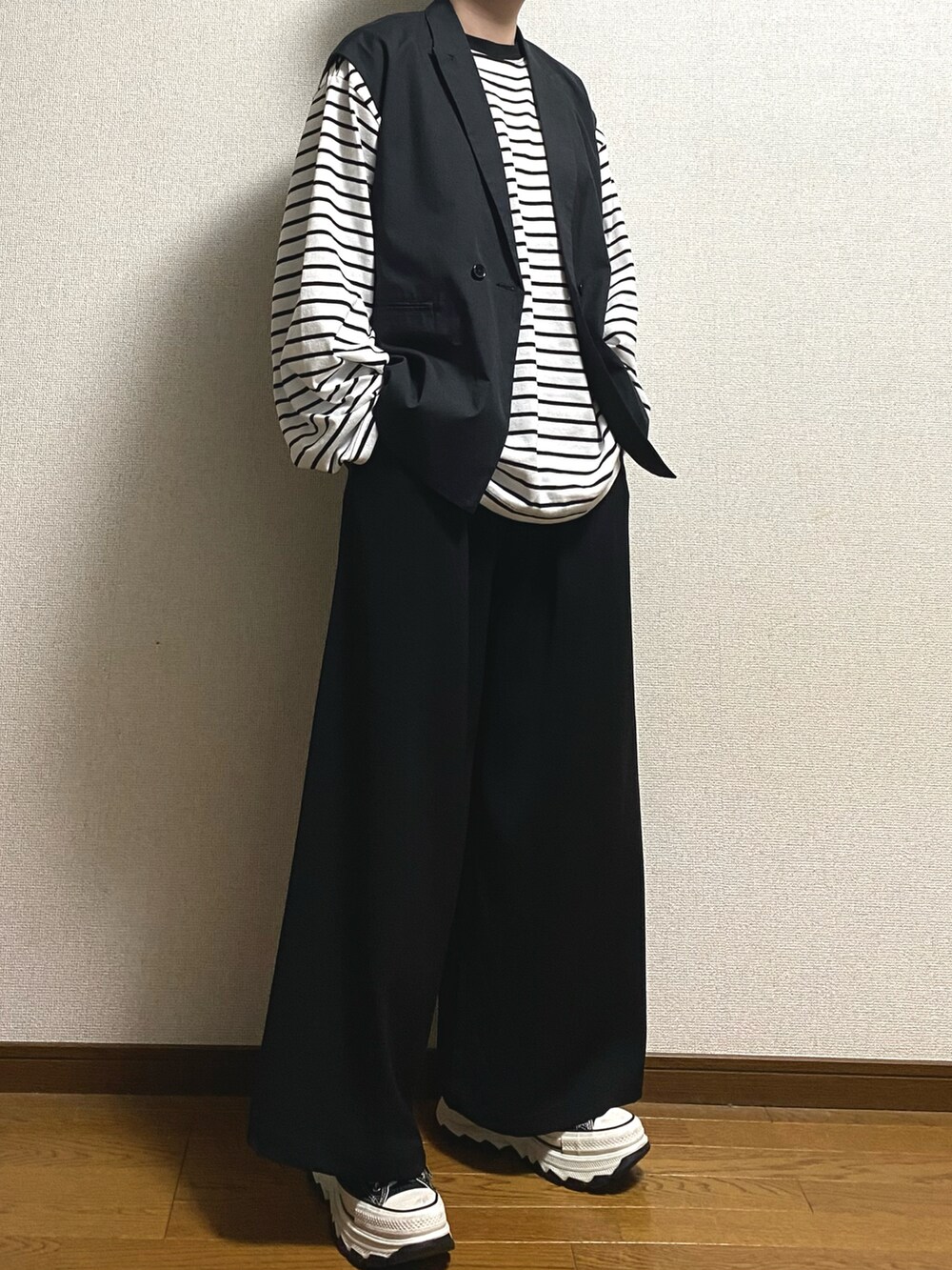 ブラック系のスニーカー、ブラック系のスラックス、ホワイト系のTシャツ/カットソーを着用したメンズの冬コーディネートの4枚目の写真