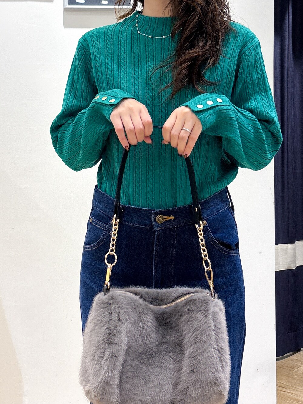 グリーン系のニット/セーター、ブルー系のデニムパンツ、グレー系のショルダーバッグを着用したレディースの秋コーディネートの4枚目の写真