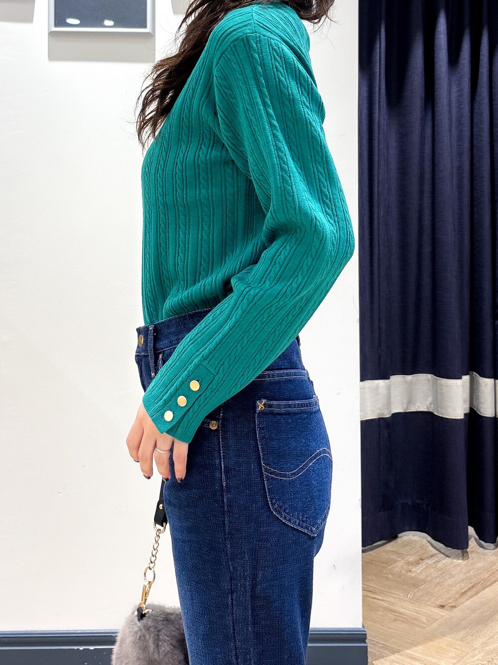 グリーン系のニット/セーター、ブルー系のデニムパンツ、グレー系のショルダーバッグを着用したレディースの秋コーディネートの5枚目の写真