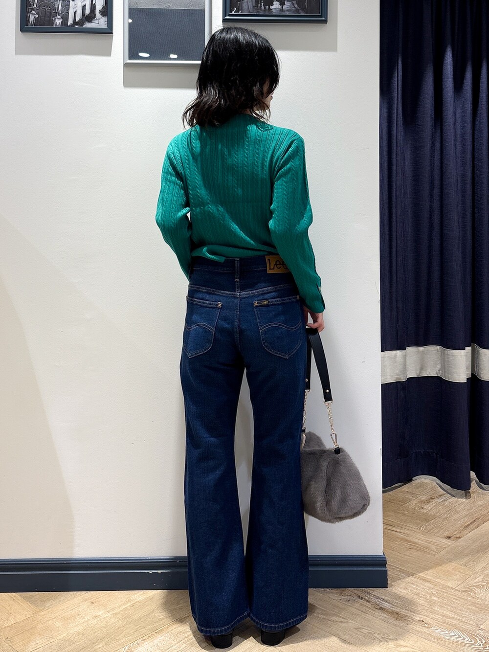 グリーン系のニット/セーター、ブルー系のデニムパンツ、グレー系のショルダーバッグを着用したレディースの秋コーディネートの3枚目の写真