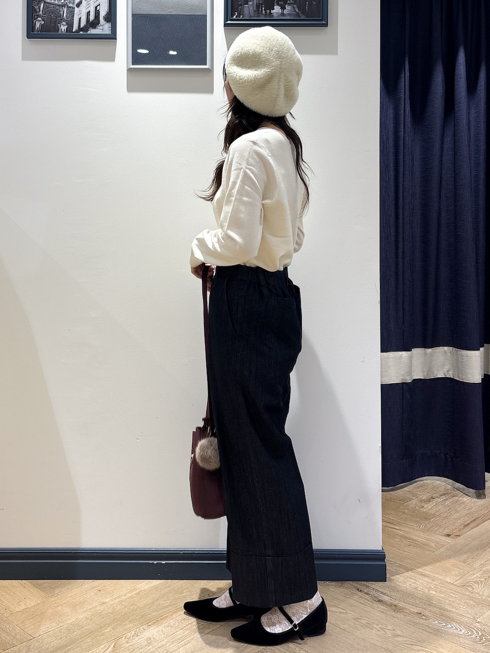ホワイト系のニット/セーター、ブラック系のデニムパンツ、レッド系のショルダーバッグを着用したレディースの秋コーディネートの2枚目の写真