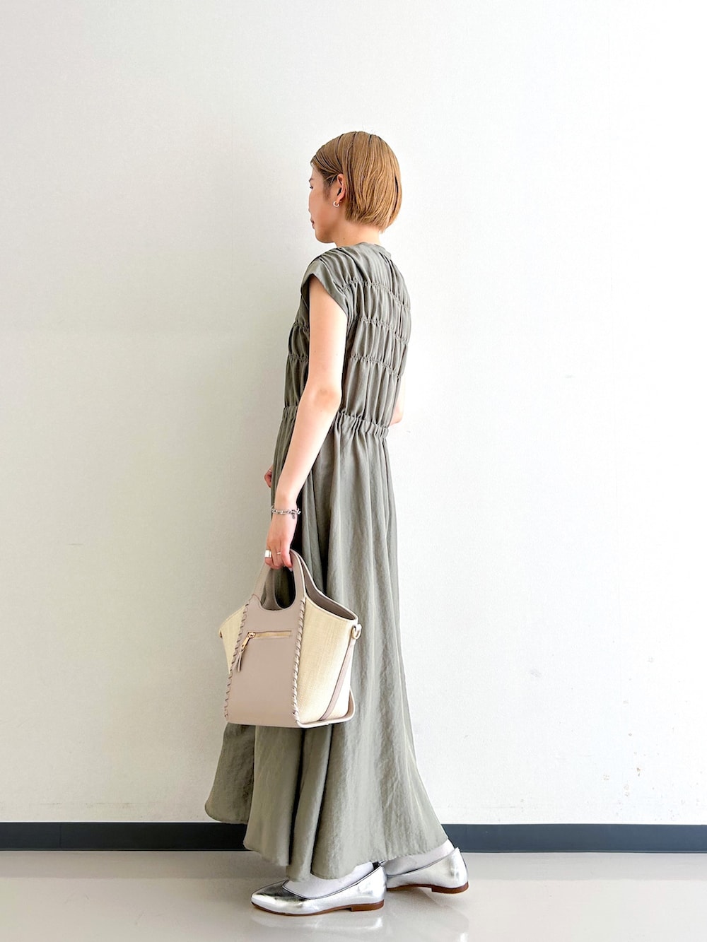 グリーン系のワンピース、グレー系のトートバッグ、シルバー系のその他シューズを着用したレディースの春コーディネートの2枚目の写真